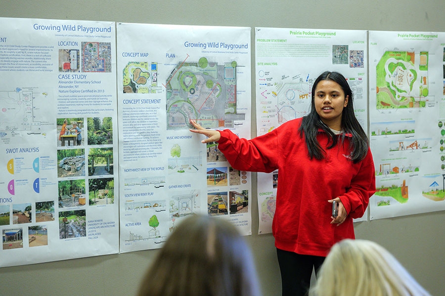 Student pointing at printout of landscape architecture designs